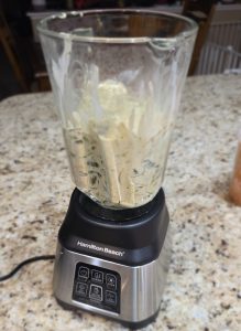 Sautéed Poblano chiles, onions, and garlic transferred from a skillet into a Hamilton Beach blender, ready to be processed into a savory base for Scofield Fruits' Poblano Cream Sauce.