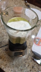 Blending fresh Mexican crema into roasted Poblano sauce to achieve a smooth, silky consistency for chicken enchiladas.