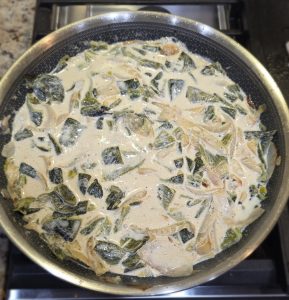 Sliced roasted Poblano chiles, caramelized onions, and garlic simmering in a rich cream and spice mixture in a stainless steel skillet for Scofield Fruits' Poblano Cream Sauce.
